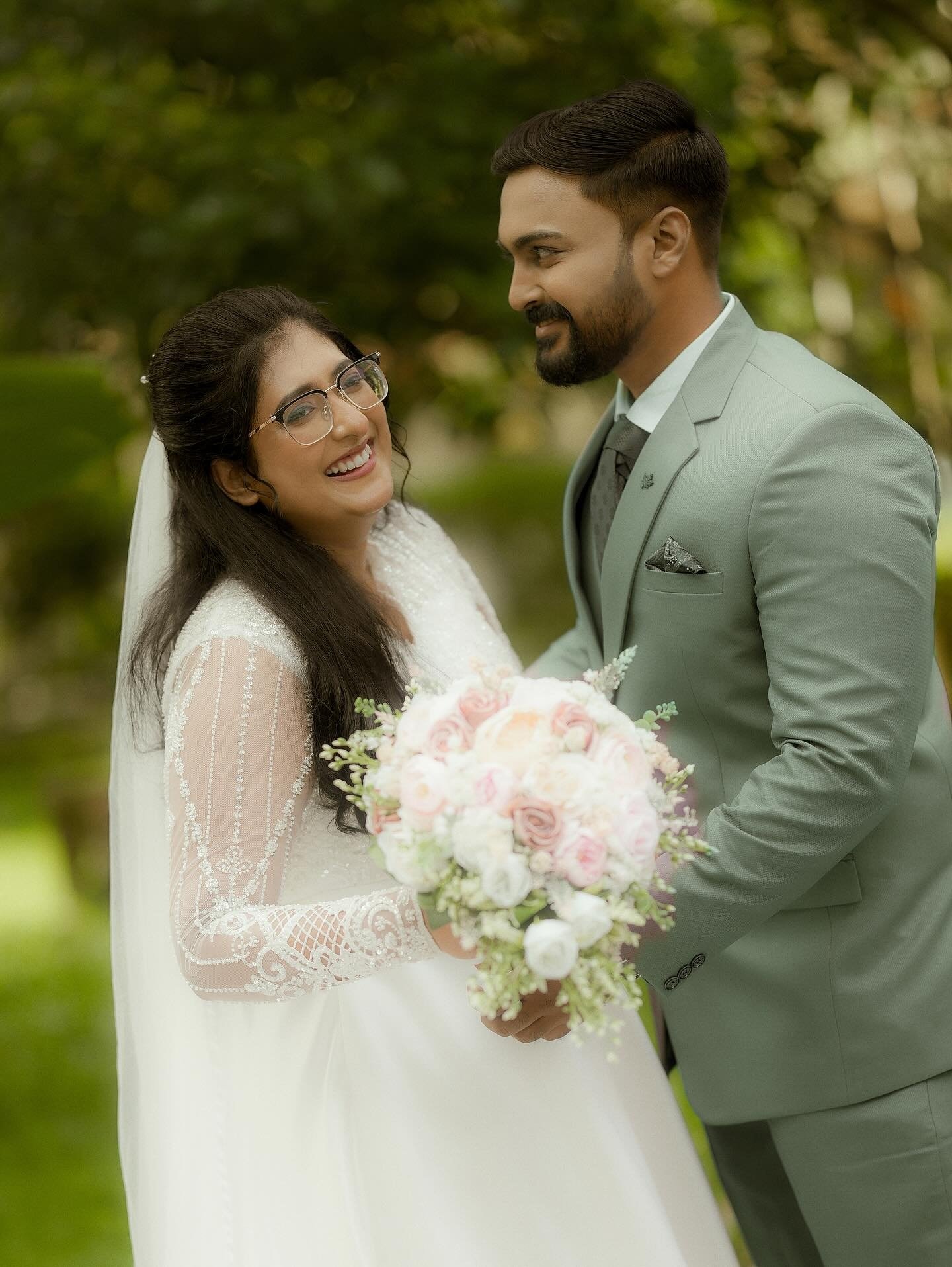 A bride and groom holding hands beneath the trees